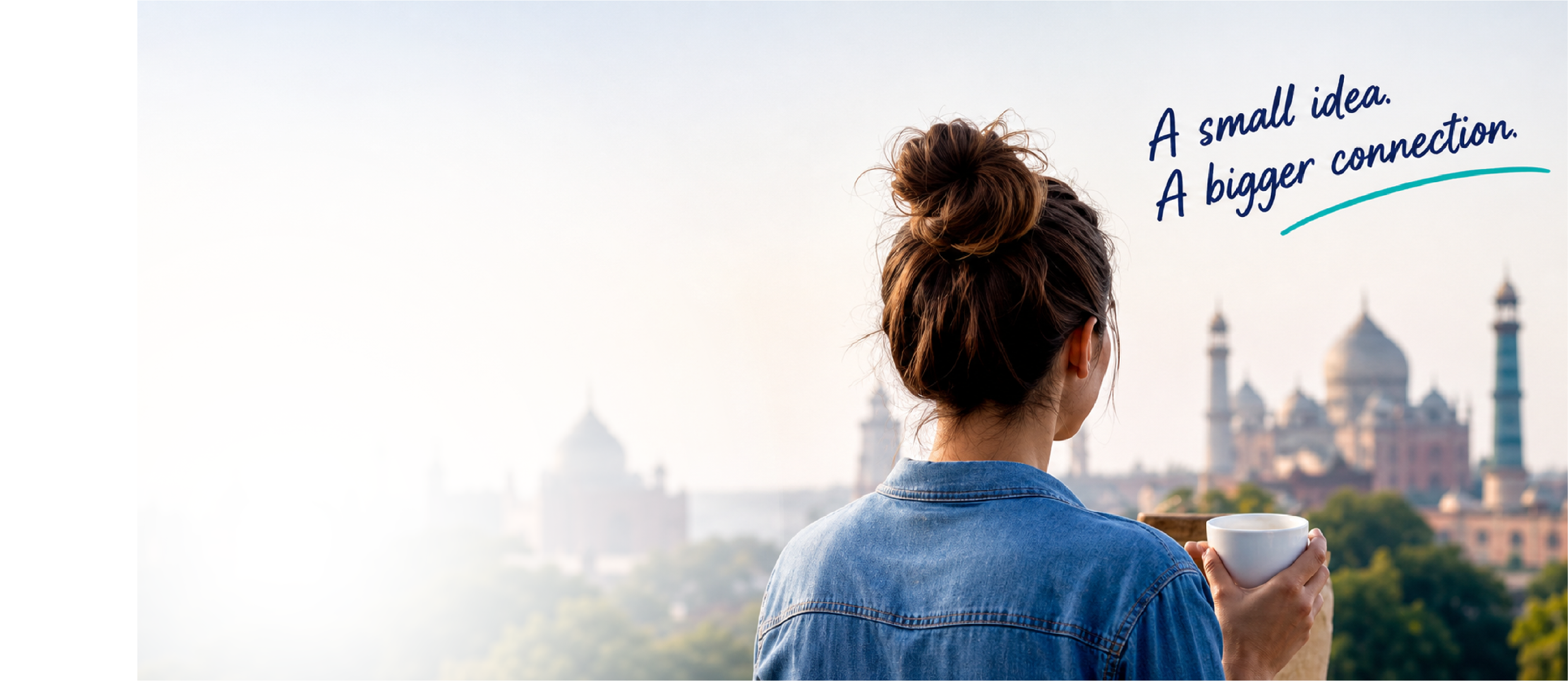 Woman looking out over a city skyline, holding a cup